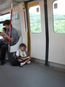 Great independent bookish small kid. Unrelated boring adult on phone behind.
